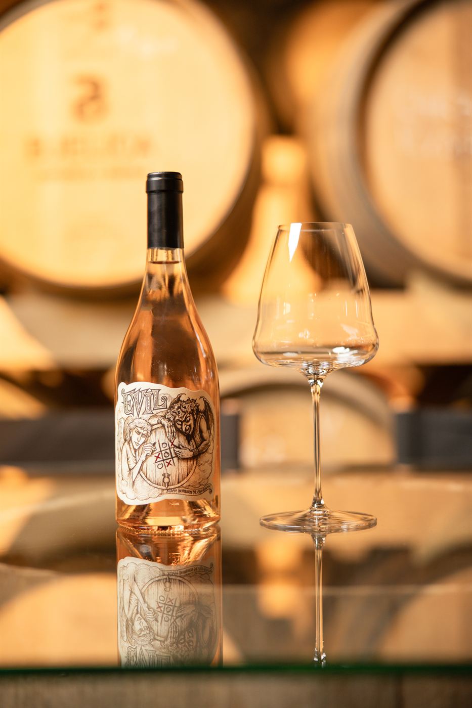 Boca roze vina Evil sa čašom ispred barik buradi